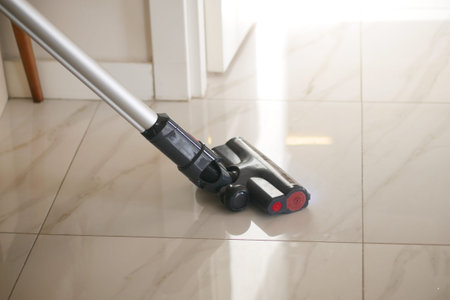 Vacuum cleaning on shiny tiled floor in bright room