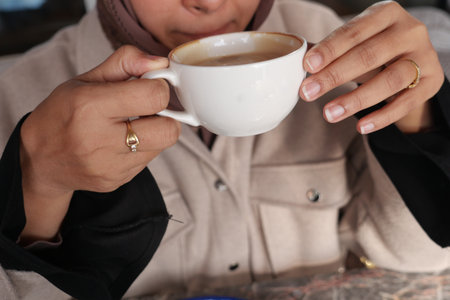 Woman enjoying a warm cup of coffee in a cozy settingの写真素材