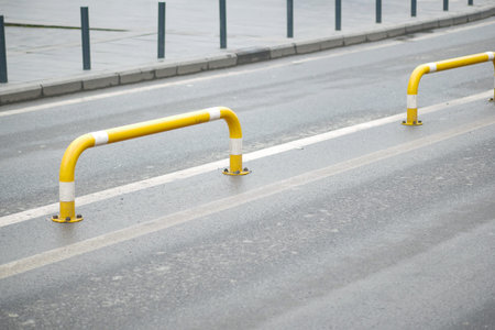 Yellow barriers on a wet urban street during a cloudy day