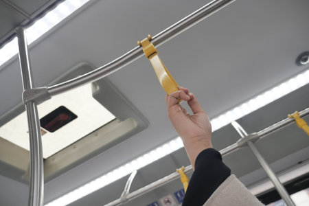 Hand gripping yellow strap in public transport setting