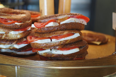 Sandwiches with tomato and cheese stacked on wooden display