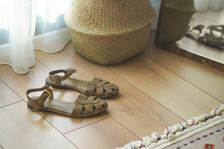 Stylish brown sandals placed near a decorative basket