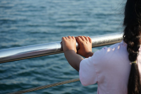 Child enjoys the view while holding onto a boat railing