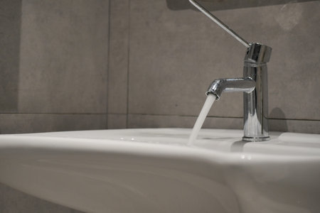 Water flowing from a modern faucet in a bright bathroom