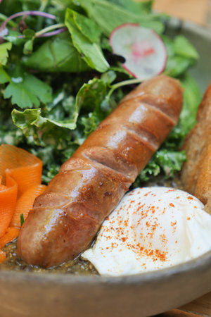 Delicious breakfast dish with sausage, greens, and eggの写真素材