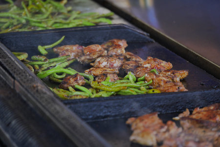 Sizzling chicken and peppers on a grill at a food stall