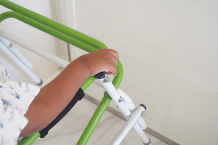 Close-Up of Childs Hand Gripping a Green Walker for Support