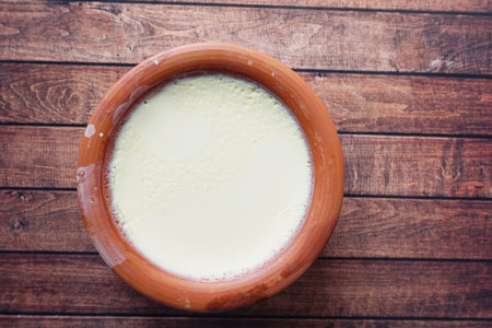 top view of yogurt in a clay container on wooden tableの写真素材