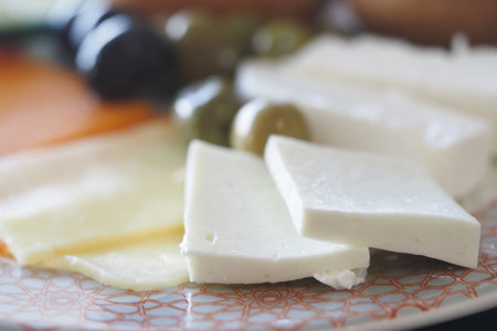 Delicious selection of fresh cheeses and olives on a plateの写真素材