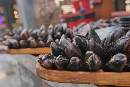 Fresh mussels arranged neatly on wooden trays at market