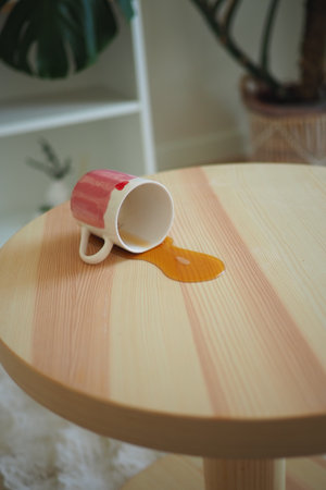 Coffee cup tipped over on wooden table creating a spillの写真素材