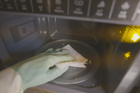 Cleaning the microwave with a cloth in a kitchenの写真素材