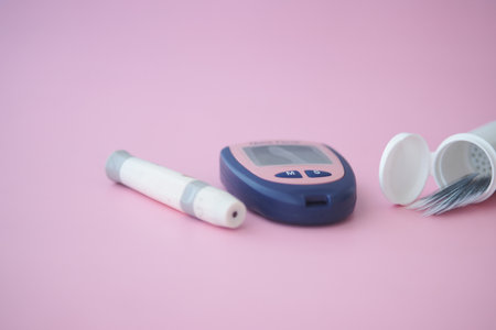 Diabetes tools on a pastel pink surface. glucose meter and suppliesの写真素材