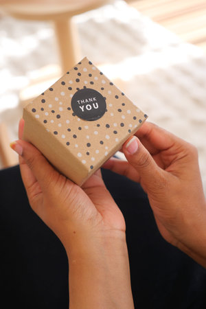 Gift box being opened with thank you note on a sunny day
