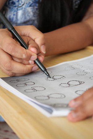 Child practices drawing shapes with a pen on paper