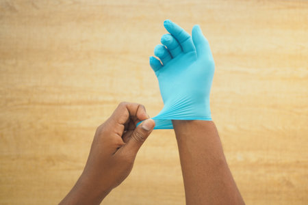 Person putting on blue medical gloves in a clean settingの写真素材