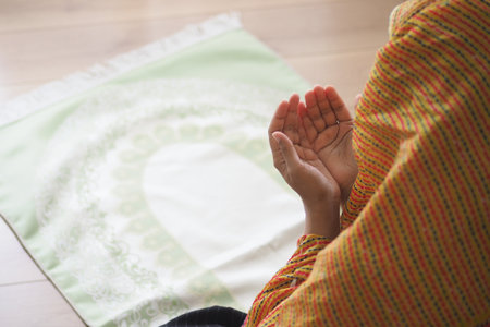muslim woman hands poised in prayer at homeの写真素材