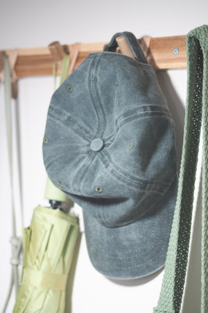 Gray cap hanging on peg with green strap nearby