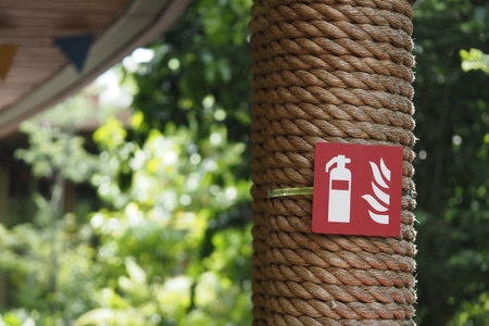 Fire safety sign on a rustic wooden pillar outdoorsの写真素材