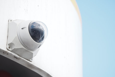 Security camera mounted on wall against a clear skyの写真素材