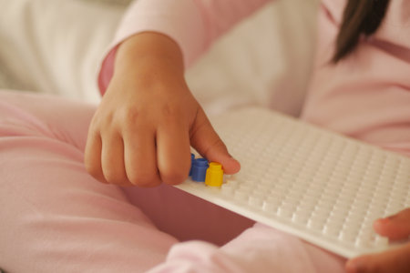 Close-Up of a Childs Hand Building with Colorful Interlocking Blocksの写真素材