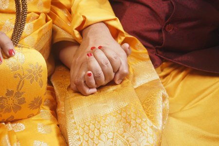 Couple holding hands in traditional attire during ceremonyの写真素材
