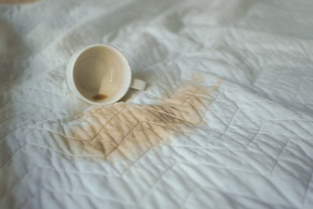 Coffee spills on white fabric in cozy indoor settingの写真素材