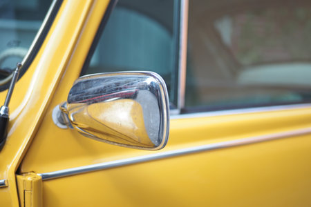 Classic yellow car with shiny side mirror close-upの写真素材