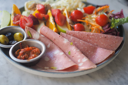 Delicious platter of fresh fruits and cold cuts on a tableの写真素材