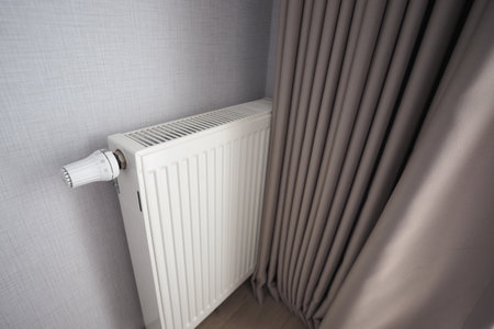 Radiator positioned beside a light gray curtain in a roomの写真素材