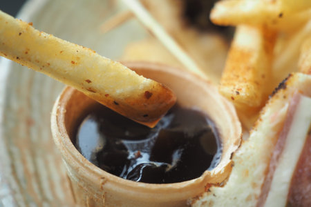 Savory fries dipped in rich sauce at a cozy restaurantの写真素材
