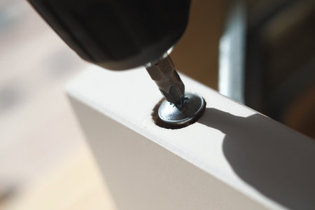 Screw driver attaching metal screw to wooden pieceの写真素材