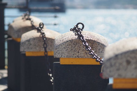 Pillars and chains along a peaceful waterfront promenadeの写真素材