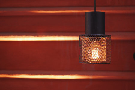 Decorative hanging light illuminates a warm orange wallの写真素材