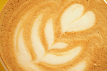 Coffee art displays a beautiful latte design in warm tonesの写真素材