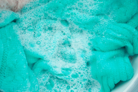 Washing bright turquoise fabric in soapy waterの写真素材