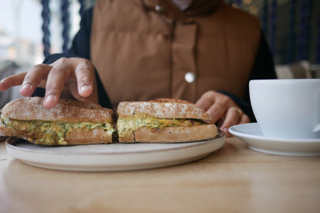 Enjoying breakfast with a sandwich and coffee at a cafeの写真素材