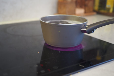Water boiling in pot on induction cooktop in kitchenの写真素材
