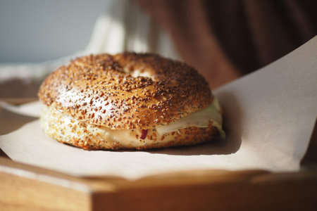 Delicious bagel with cream cheese on a wooden surfaceの写真素材