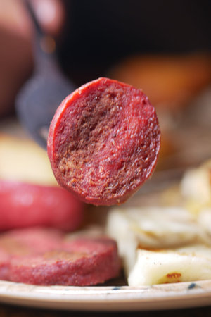 Delicious slice of sausage held above hearty breakfast meal