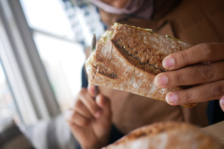 Holding a fresh baked sandwich in a cozy cafeの写真素材