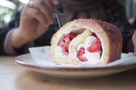 Sweet dessert roll with strawberries and cream on a plateの写真素材