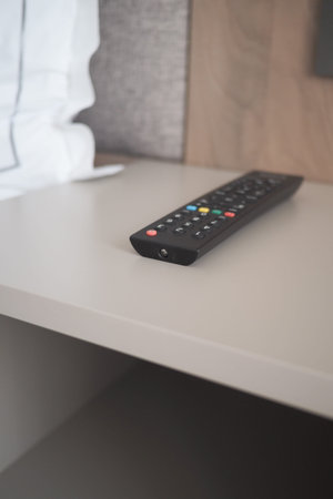 Remote control placed on a bedside table in a roomの写真素材