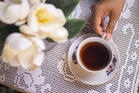 Enjoying a cup of tea on a lace tableclothの写真素材