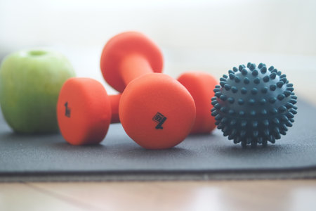 Colorful weights, apple, and massage ball on exercise matの写真素材