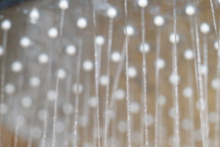 Close-up view of droplets hanging from a showerheadの写真素材
