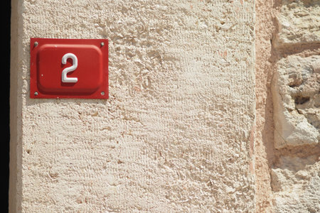 House number two on a textured wall in bright sunlightの写真素材