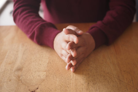 Hands resting on a wooden table in a calm setting