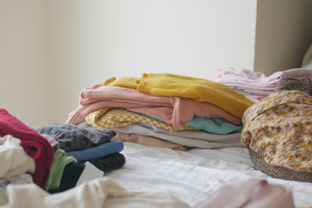 Neatly folded clothes on a bed in a cozy roomの写真素材