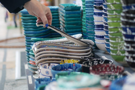 Hand selecting colorful ceramic bowls in a market stall